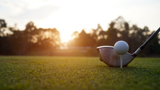 Golf clubs and golf balls on a green lawn in a beautiful golf course with morning sunshine.