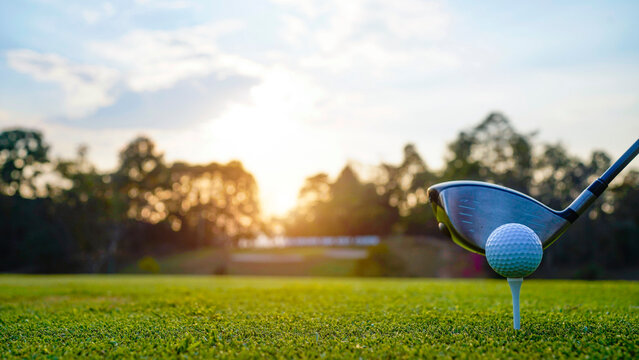 Golf clubs and golf balls on a green lawn in a beautiful golf course with morning sunshine.