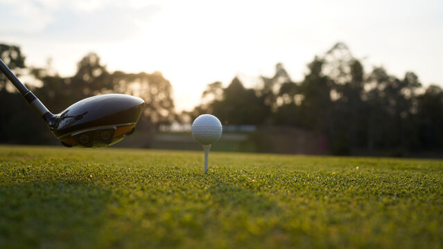 Golf clubs and golf balls on a green lawn in a beautiful golf course with morning sunshine.