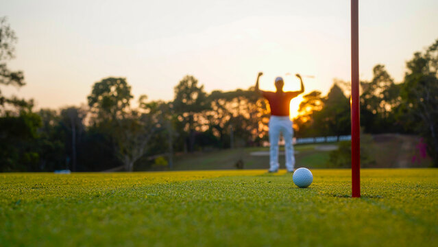 Golfer putting ball on the green golf, lens flare on sun set evening time.