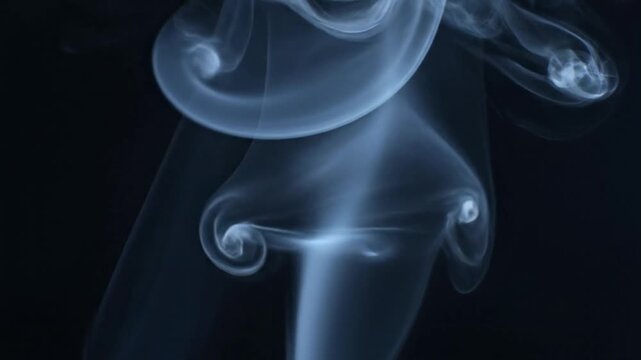 Smoke swirls around a person's body in a dark room creating an abstract effect.