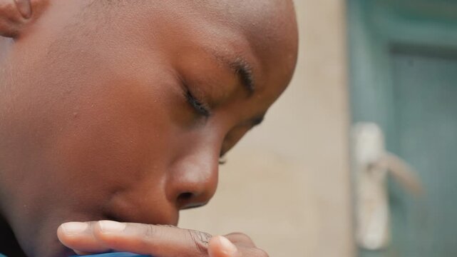 Young boy prepares to release balloon outside. Boy cautiously inflates bright blue balloon outdoors. Young boy takes time to inflate colorful balloon carefully in outdoor environment