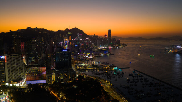 Hong Kong - 14 February 2026: Aerial view of Victoria Harbour and the illuminated skyline under a vibrant orange sunset sky.