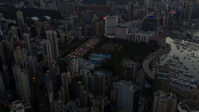 Hong Kong - 14 February 2026: Aerial view of Victoria Harbour and the dense urban skyline with illuminated skyscrapers and Victoria Park at dusk.
