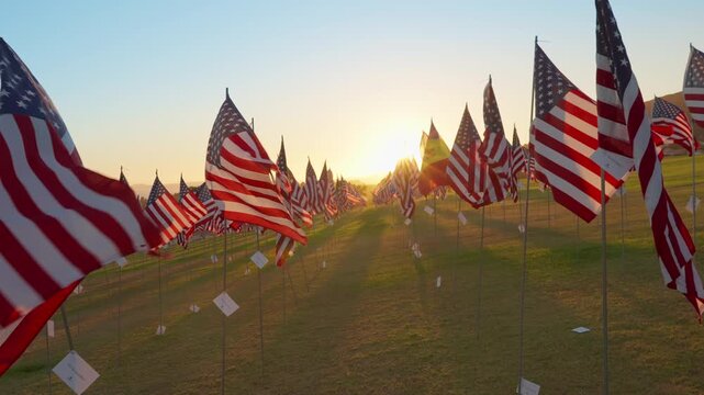 Sunset light glowing over American flags memorial in Malibu, California, USA with warm tones and waving flags creating strong patriotic tribute and emotional remembrance scene. Slow motion