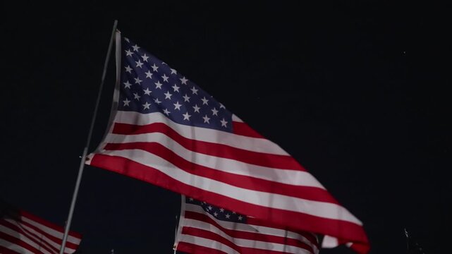 American flag detail at night in Malibu, California, USA with strong lighting and wind movement, fabric waves creating cinematic patriotic memorial scene
