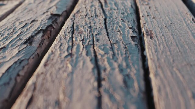 A close-up glides over weathered wooden planks with deeply cracked, peeling white paint under warm light. Concept of aging, natural decay, rustic textures, and the passage of time.