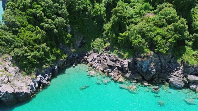 Cinematic drone tracking shot along the lush green cliffs of Pelion. High-angle view of the vibrant turquoise Aegean sea, golden sand and iconic rock formations. Ideal for travel and nature films.