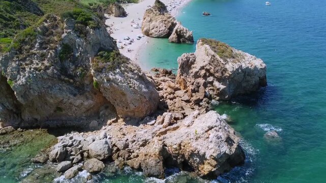 Cinematic drone shot flying over a giant rock formation to reveal the hidden Potistika beach. High-angle top-down view of turquoise Aegean waters and golden sand. Stunning coastal landscape. No audio.