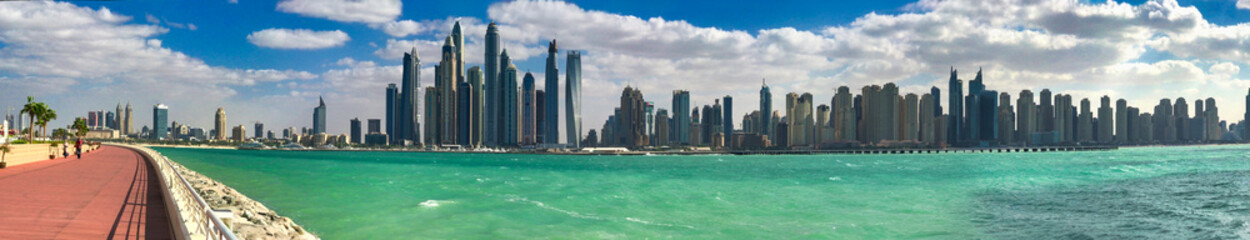 Fototapeta premium Stunning Dubai Marina skyline towering above pristine beach with modern skyscrapers against clear horizon line