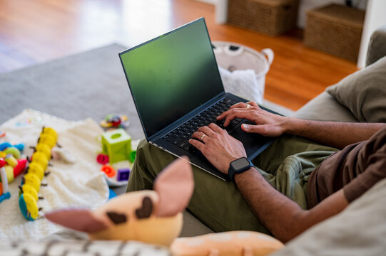 Indian man sitting on the couch in the living room working on his laptop