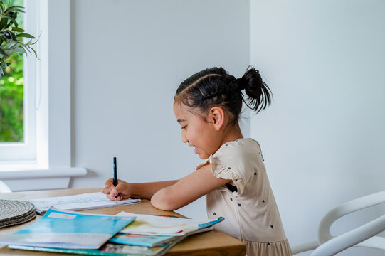 Young Samoan girl sitting behind wooden table doing her homework