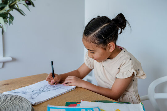 Young Samoan girl sitting behind wooden table doing her homework