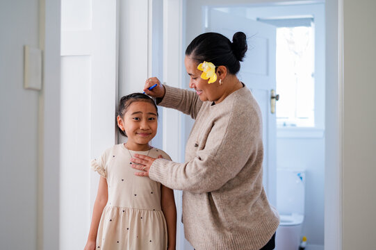 Young Samoan girl standing against the wall while mum measures her height