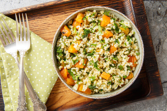 Low-calorie dietary bulgur with parsley and dried apricots close-up in a bowl on the table. Horizontal top view from above