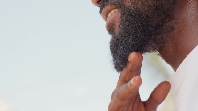 Outdoor grooming confidence. Man confidently styles his beard outside. Man outdoors carefully shaping his beard confidently. External grooming session with man confidently managing his beard shape
