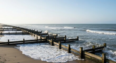 Obraz premium Scenic coastal view of wooden groynes on a sandy beach.