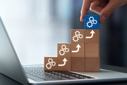 Productivity growth through automation tools and system integration. Businessman stacking wooden cubes on laptop keyboard.