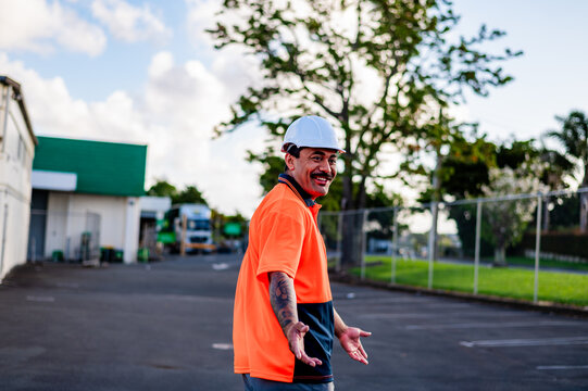 A cheerful construction worker with a hard hat greets people at a work site