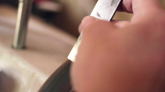 Skilled artisan hands using a sharp chisel to carve fine wood shavings from a timber block. Close-up slow motion shot.