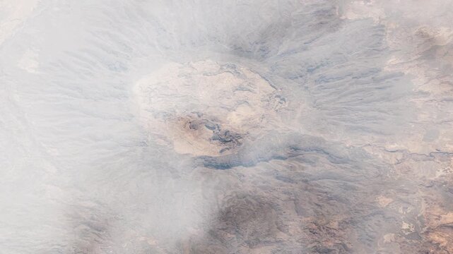 Flying over Tah de Zoumri massif Chad geological formation satellite view from space with passing clouds based on Nasa imagery