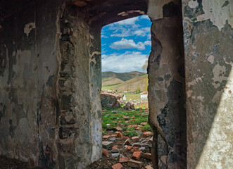 Naklejka premium Broken wall shows view of mountain landscape and cloudy sky in remote area during day