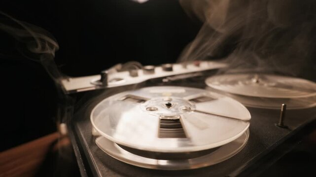 A vintage reel-to-reel tape recorder spins slowly while engulfed in thick cinematic smoke. Concept of retro music nostalgia, classical espionage, and vintage audio technology.