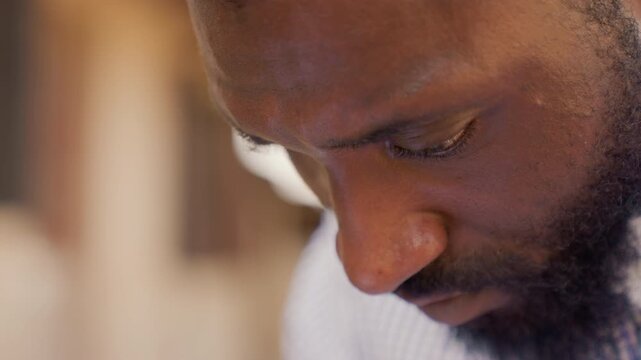 Black man extreme closeup reading, intense editorial focus with furrowed brow and beard, cinematic warm light, macro detail on skin texture and eyes, mood of determination during proofreading