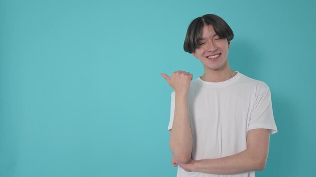 Smiling young man pointing with his thumb