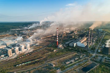 Industrial pollution causes environmental degradation in a large manufacturing facility with smoke and emissions during daytime © Evgenii Bakhchev