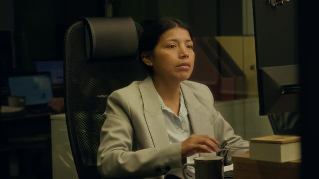 Medium shot of Hispanic female accountant working overtime to deadline on quarterly financial report at night in office, struggling to stay awake, putting on glasses with cartoon eyes and nodding off