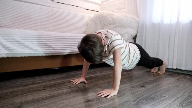 Nine year caucasian Boy Doing Push-ups at home. Sporty child. Kids workout activity. Concept of Future Athlete, Determination and endurance. High quality 4k footage.
