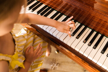 Fototapeta premium Cute child playing piano indoors learning music childhood education creativity talent and practice