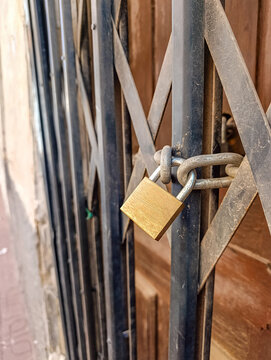 Locked Metal Gate with Padlock on Old House