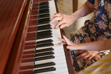 Fototapeta premium Senior woman guiding child piano practice at home music education family care and generational wisdom