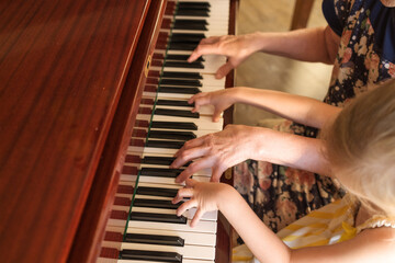 Fototapeta premium Grandmother teaching child piano at home music learning childhood and generational connection