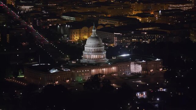 Aerial night shot of the illuminated U.S. Capitol and surrounding streets, highlighting its iconic dome.