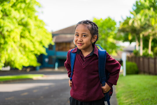 Portrait of Maori school boy standing on the sidewalk carrying his backpack