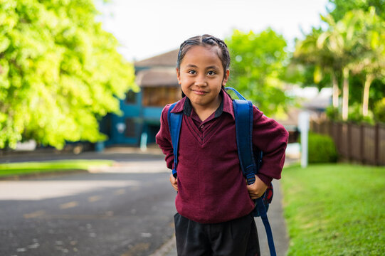 Portrait of Samoan school boy standing on the sidewalk carrying his backpack