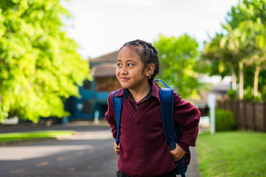 Portrait of Samoan school boy standing on the sidewalk carrying his backpack