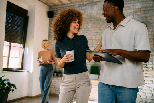 Smiling multi-ethnic colleagues engaging in conversation while walking in a modern office space