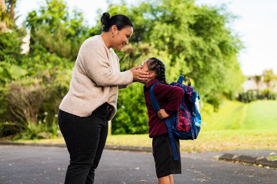Niuean mum bending down holding her face and giving son a soft kiss