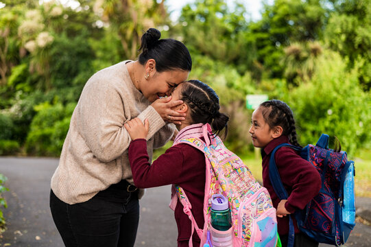 Niuean mum bent down holding daughters face close to hers