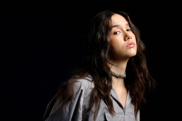 Fototapeta premium Stylish young woman showcases modern fashion in studio setting with dramatic lighting