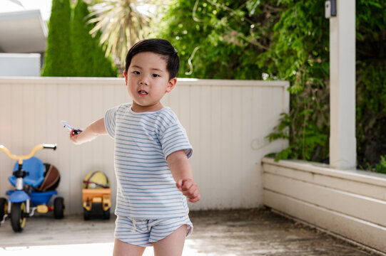 Young Asian boy playing with a toy aeroplane in the patio in motion