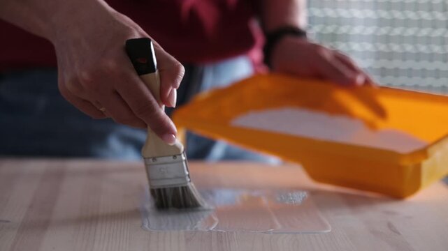 Woman Renovates Furniture By Painting A Wooden Surface With A Brush