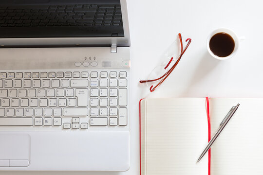 Postazione di lavoro con computer, notes, occhiali e tazzina di caff&egrave;
