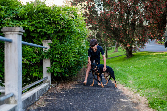 Boy walking  a dog along a pathway bordered by dense bushes in New Zealand