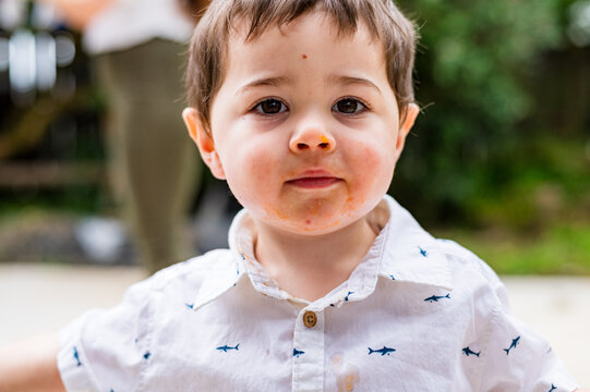 Close up of toddler boy with an orange mess on his face
