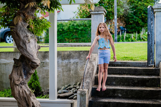 Barefoot young girl walking down concrete staircase